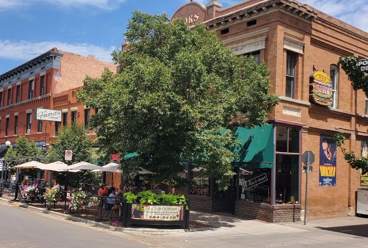Our block of B Street on a sunny day: red brick buildings, a big shade tree and patio umbrellas along the sidewalk