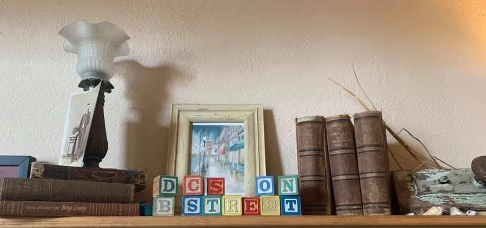 A shelf inside the restaurant with wooden letter blocks spelling DC’s On B Street, old books, a framed picture and a small lamp